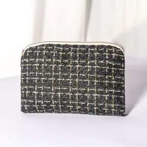 Black and gold tweed makeup pouch detail, elegant woven texture cosmetic bag close-up view.
