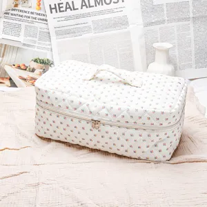 Quilted floral cosmetic bag, portable travel makeup organizer with handle and zip closure.