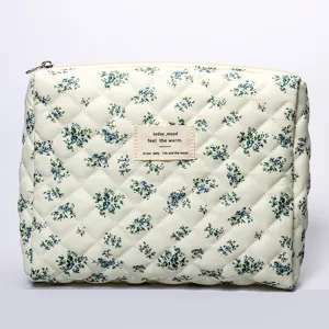 Detailed view of the quilted cosmetic bag with blue floral pattern and woven label.