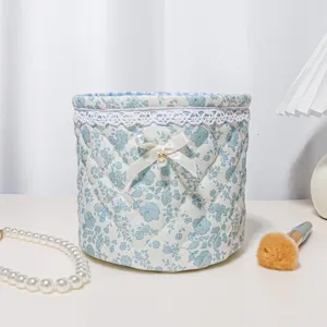 Quilted round storage basket with floral pattern, lace trim, and bow detail for desktop organization.