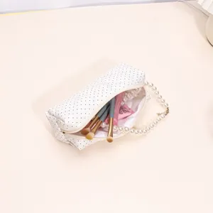 Quilted white cosmetic bag with black polka dots and elegant pearl handle for women.
