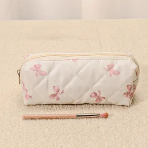 Quilted makeup pouch detail, cute bow print aesthetic cosmetic bag with smooth zipper closure.