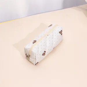 Close-up detail of the white quilted cosmetic pouch with cute bear prints and smooth zipper.