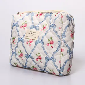 Quilted floral cosmetic bag with blue ribbon design, padded portable makeup pouch for daily use.