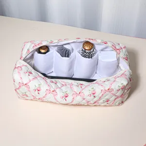 Quilted storage bag with floral ribbon pattern and multi-compartments for hair tools.