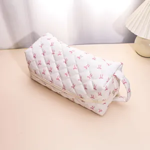 Quilted cosmetic bag with cute pink bow print, portable zipper storage for travel.