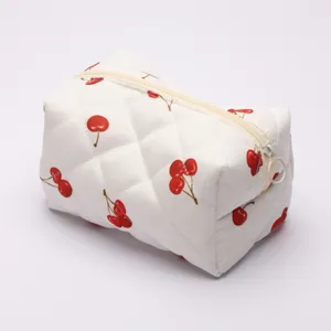 Quilted cherry cosmetic bag detail view, white makeup storage pouch with zipper closure.