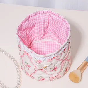 Quilted storage basket detail, pink floral fabric with bow lace trim and pink gingham interior.