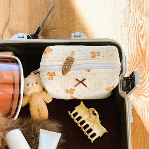 Detailed view of a cute quilted cosmetic toiletry bag with bear print and bow inside suitcase.