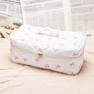 White quilted cosmetic bag with pink bows, portable travel makeup organizer storage case.