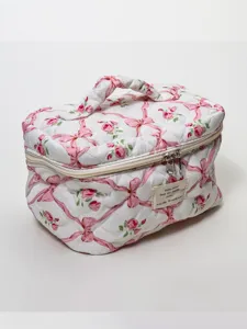 Quilted cosmetic bag detail featuring charming pink ribbon floral pattern and sturdy zipper.