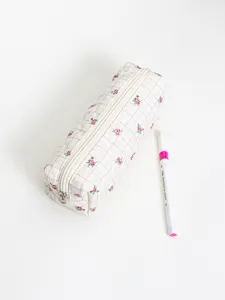 Quilted floral pencil pouch detail view, showing white plaid fabric and secure zipper closure.