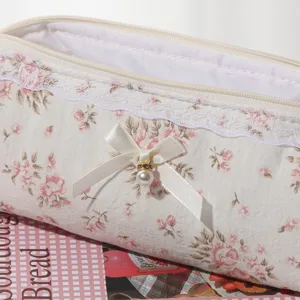 Cute floral lace cosmetic pouch detail view, portable canvas makeup brush bag with ribbon.
