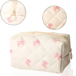 Detail view of quilted cosmetic bag featuring pink bow pattern and smooth zipper closure.