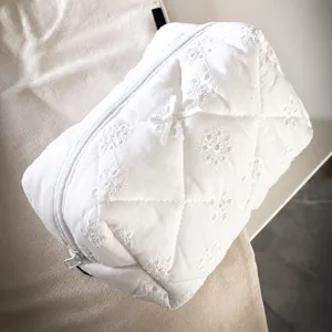 White quilted cosmetic bag with elegant floral embroidery and cute bow zipper pouch travel makeup.