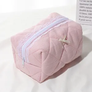 Pink quilted cosmetic bag with white lace trim, cute bow and zipper for daily travel.