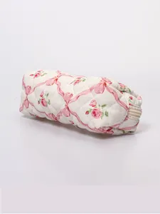 Quilted floral cosmetic pouch close-up, pink rose pattern and smooth zipper detail.