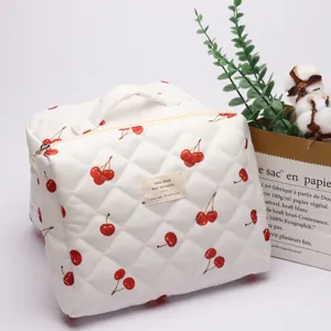Quilted cosmetic bag detail featuring adorable red cherry print, white fabric and sturdy zipper pull.