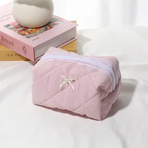 Pink waffle cosmetic bag detail featuring delicate lace zipper trim and cute bow accent.