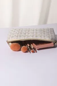 Tweed makeup bag with zipper and brushes detail close up, elegant cosmetic organizer