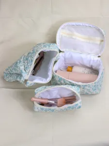 Quilted cosmetic bag set featuring blue floral print, interior mesh pockets, and zippers.