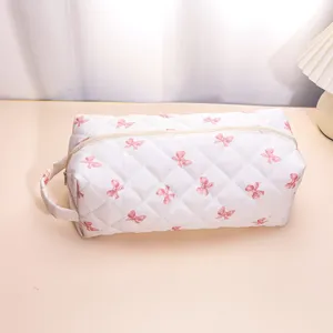 Quilted makeup bag with pink bow pattern, portable travel cosmetic storage organizer case.