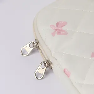 Detail der weißen gesteppten Laptoptasche mit rosa Schleifenprint und robusten Metallreißverschlüssen.