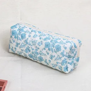 Close-up detail shot of quilted floral cosmetic pouch, blue and white pattern, zipper.
