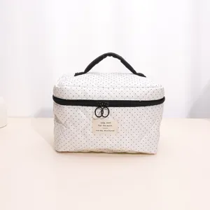 White quilted cosmetic bag with black polka dots, portable handle and secure zip closure.