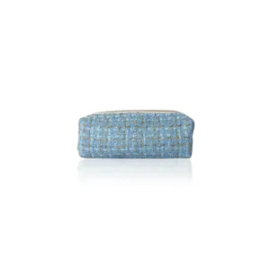 Blue tweed cosmetic pouch detail, portable woven makeup storage bag with secure zipper close.
