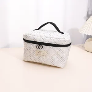 Detailed shot of the quilted polka dot cosmetic bag showcasing its zipper and label design.