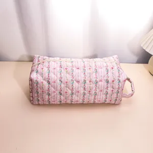 Detailed close-up of pink floral quilted cosmetic bag showing soft padded fabric texture and zipper.