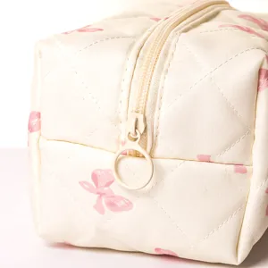 Close-up detail view of the quilted cosmetic bag zipper and soft padded fabric texture.