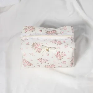 Floral cosmetic bag detail, cute bow charm and zipper closure, portable toiletry storage.