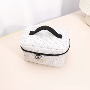 White quilted cosmetic bag with black polka dots, portable handle, and large storage capacity.