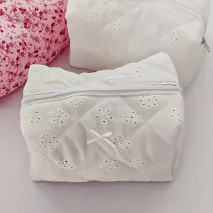 Detailed shot of white cosmetic bag with delicate floral pattern and cute bow for travel.