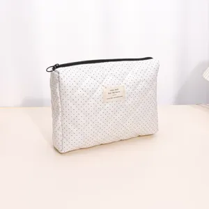 Detail view of quilted cosmetic pouch with polka dots and zipper, soft fabric storage bag.