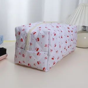 Padded cosmetic storage bag with cute cherry and bow print, portable quilted zip pouch for travel.