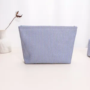 Blue and white striped fabric cosmetic bag detail, featuring durable zipper closure and neat stitching.
