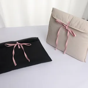 Close-up detail of quilted laptop sleeve in beige and black with cute pink ribbon bow ties.