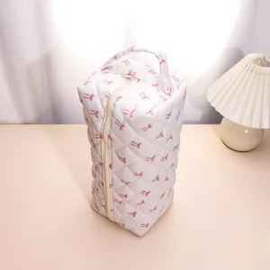 Detailed shot of white quilted travel storage bag with pink bow pattern and sturdy zipper.