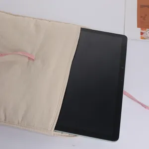 Quilted beige laptop sleeve with pink ribbon bow tie, soft padded tablet bag detail.