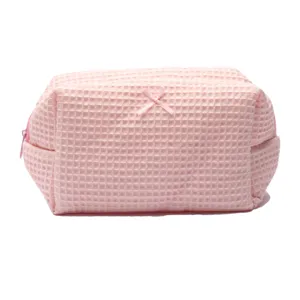 Pink waffle cosmetic bag for women, cute bow travel makeup pouch with zipper closure.