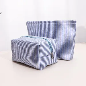 Detailed view of blue and white striped cosmetic bags set, featuring large capacity and zipper.