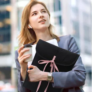 Detail shot of black quilted laptop sleeve with cute pink bow strap in urban street setting.