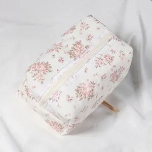 Quilted floral cosmetic bag featuring delicate lace trim and zipper closure. Detail view.