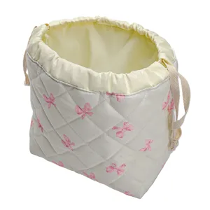 Quilted drawstring cosmetic bag detail, soft fabric makeup storage pouch with pink bow print.