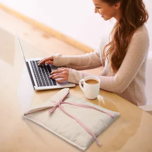 Detailed lifestyle view of beige padded laptop sleeve with pink ribbon ties for daily use.
