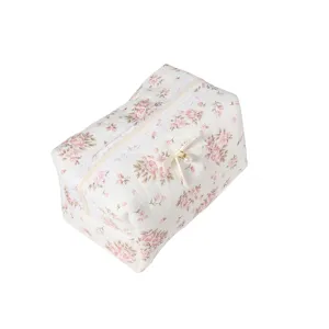 Detailed view of quilted floral cosmetic bag with lace trim, bow, and pearl charm detail.
