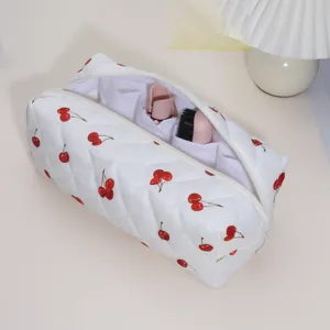 Close-up detail of white quilted cherry print cosmetic and hair styling tool storage bag.